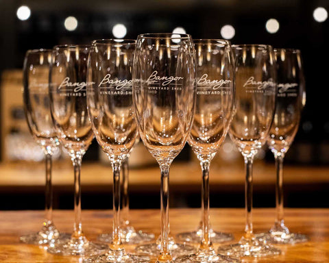 Set of wine glasses with 'Bangor' branding on the wooden Bangor wine bar.