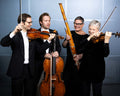 Four musicians from the Tasmanian Symphony Orchestra playing string instruments against a plain background