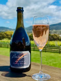Bottle and glass of Bangor sparkling rose wine with a scenic background