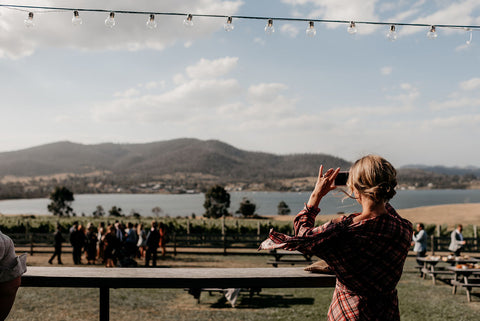 Person taking a photo of a scenic view with mountains and a lake. Image: Fiona Vail Photography.