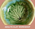 A ceramic bowl with a glossy green leaf design and blue-green glaze accents, shown against a dusty pink background with the text 'ADULTS CLAY WORKSHOP' at the bottom.