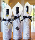 Three Bangor wine bottles gift wrapped in Bangor paper with black ribbons.